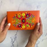 an orange jewelry box with colorful flowers